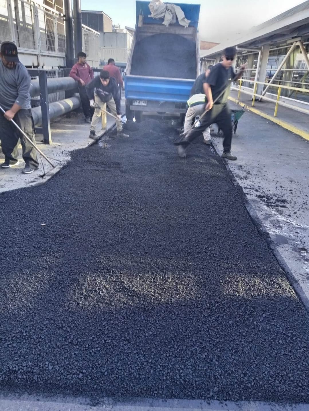 Cuadrilla extendiendo mezcla asfáltica manualmente
